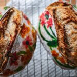 two loaves of baked sourdough bread with painted flowers