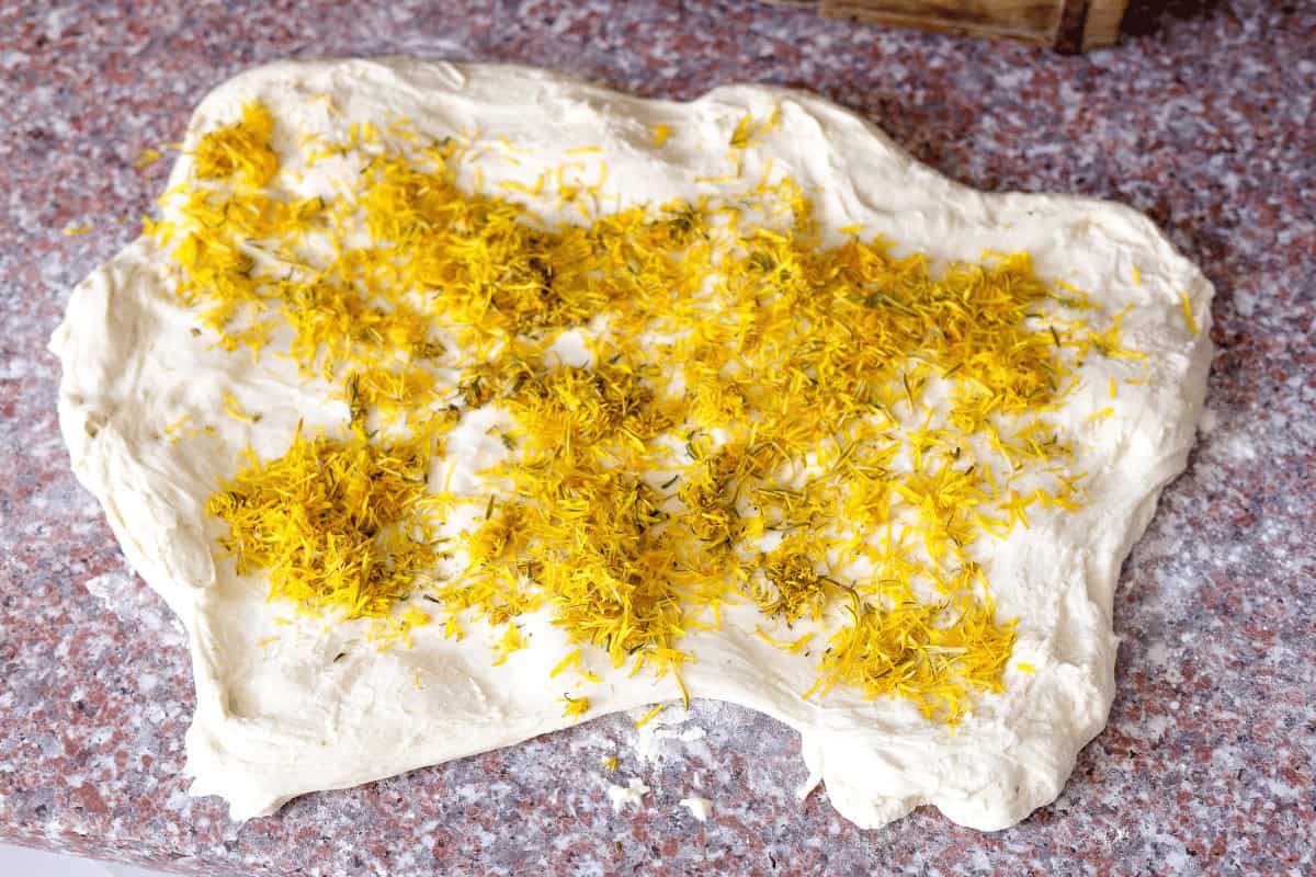 folding dandelion flowers in the dough