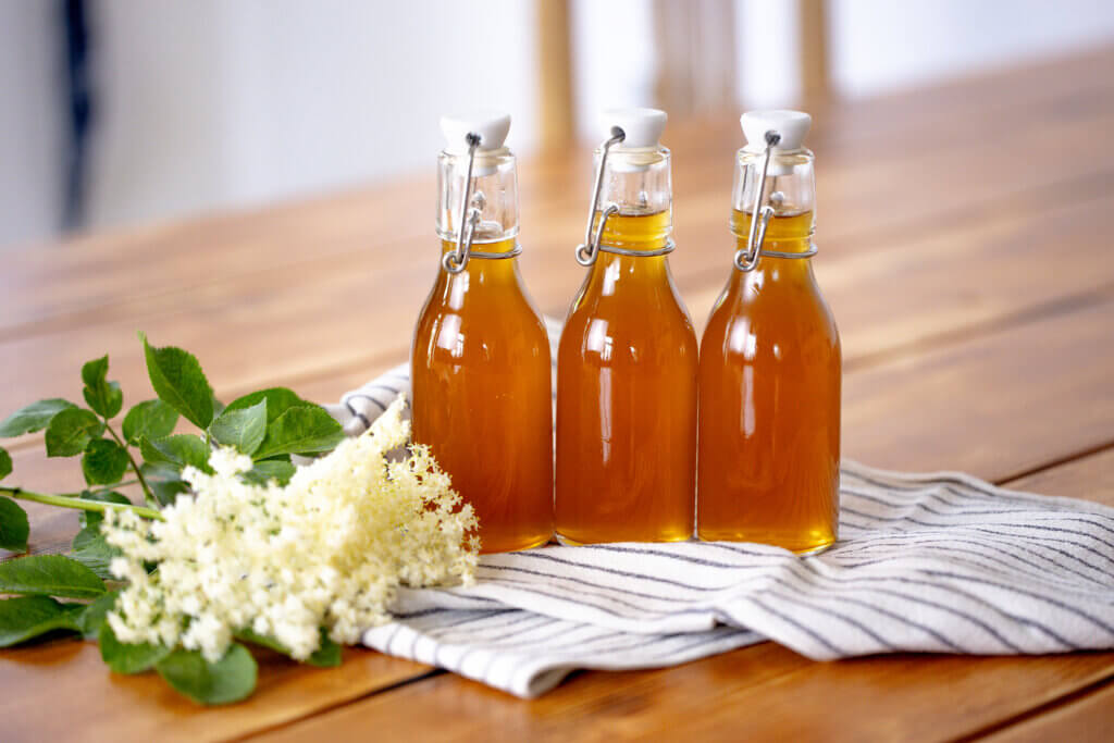 bottles of elderflower syrup with elderflower