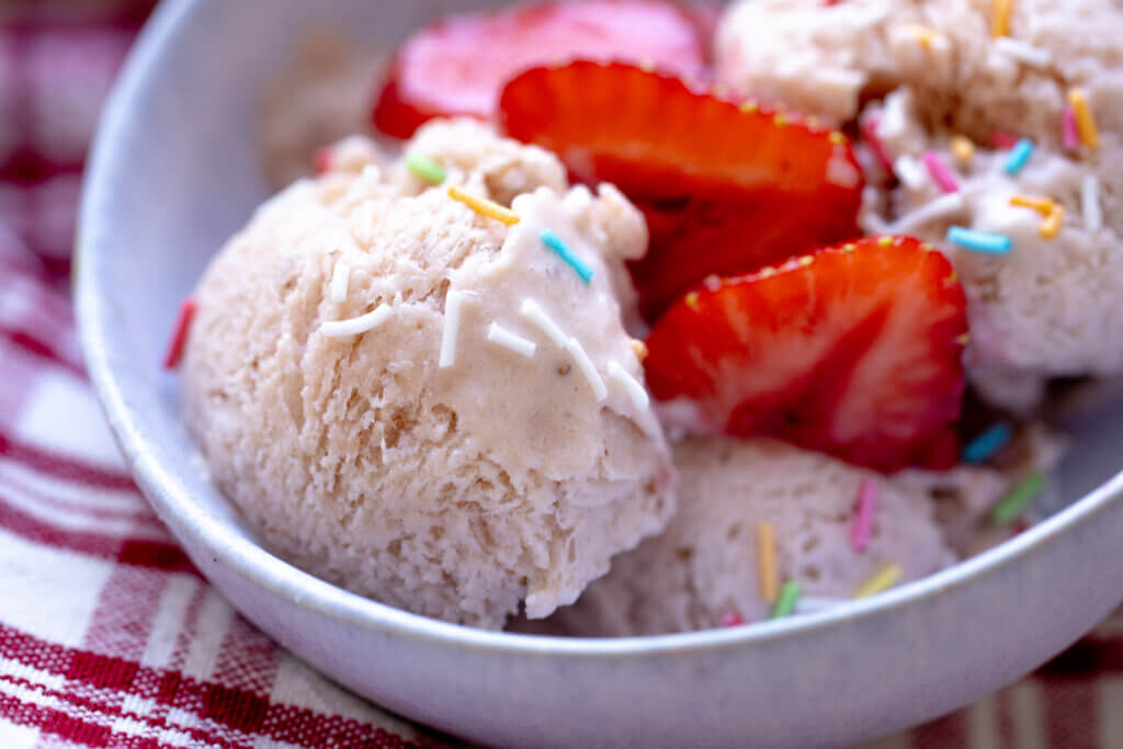 a close up of ice cream with sliced strawberries on top
