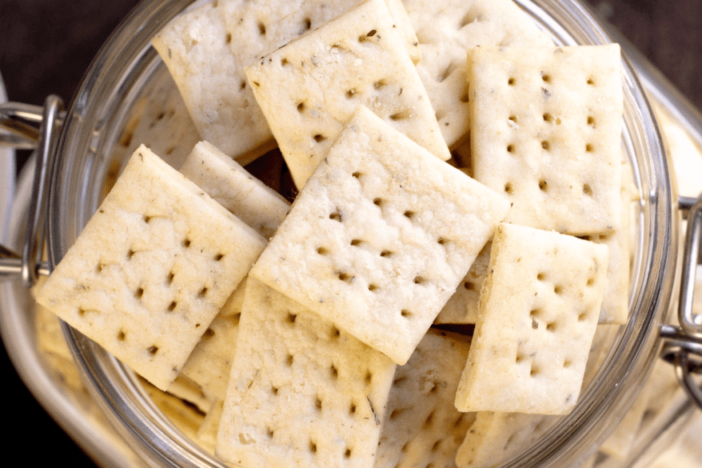 a close up view of sourdough crackers overflowing in a jar