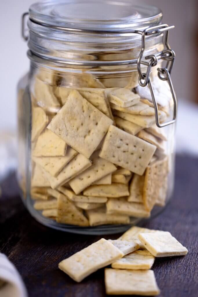 crackers inside a closed jar with some pieces beside it 